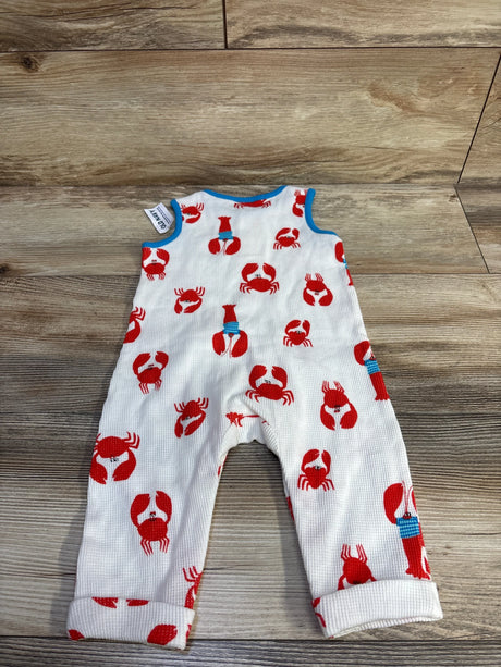 Flat-lay of Old Navy sleeveless waffle-knit henley jumpsuit showing red crab print, blue trim, and rolled cuffs on wood floor