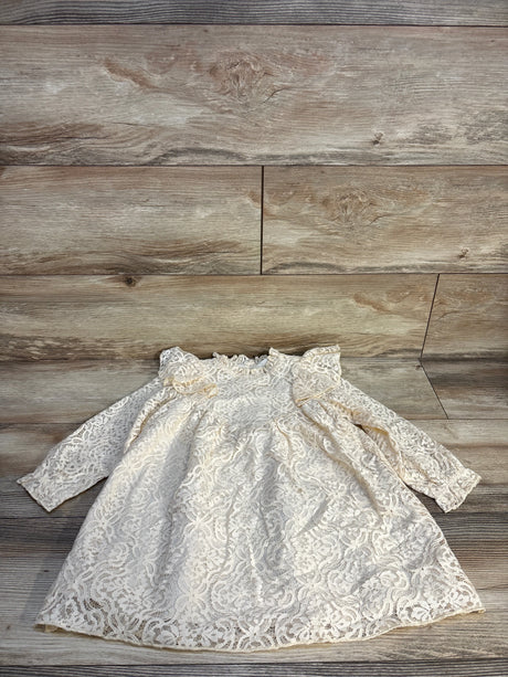 White lace long sleeve baby dress with floral pattern on wood background