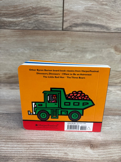 Back view of Machines At Work board book showing green dump truck illustration on orange background on wood floor