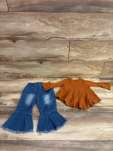 Top-down view of Kucnuzki two-piece outfit showcasing a ribbed brown ruffle top and blue bell-bottom jeans on wood-look flooring