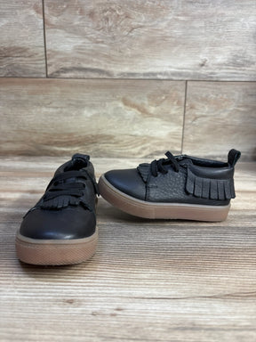 Black toddler fringe sneakers with tan soles on wood floor