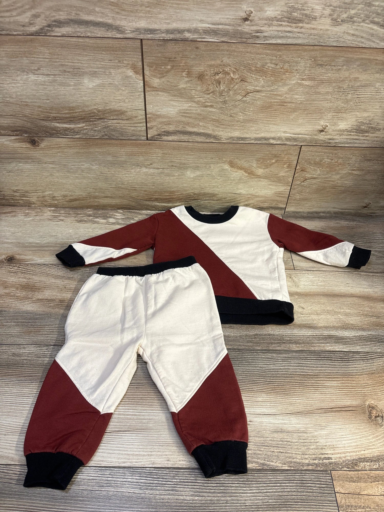 Front view of Mini Threads red and cream sweatshirt and joggers set for 12 months showing color-block design on wood floor