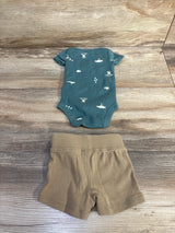Flat-lay of newborn 2-piece Child Of Mine bodysuit and shorts set showing green printed short-sleeve bodysuit and tan elastic-waist shorts on wood background