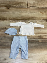 Baby outfit set with white long sleeve shirt, blue hat, and blue printed pants on wood background