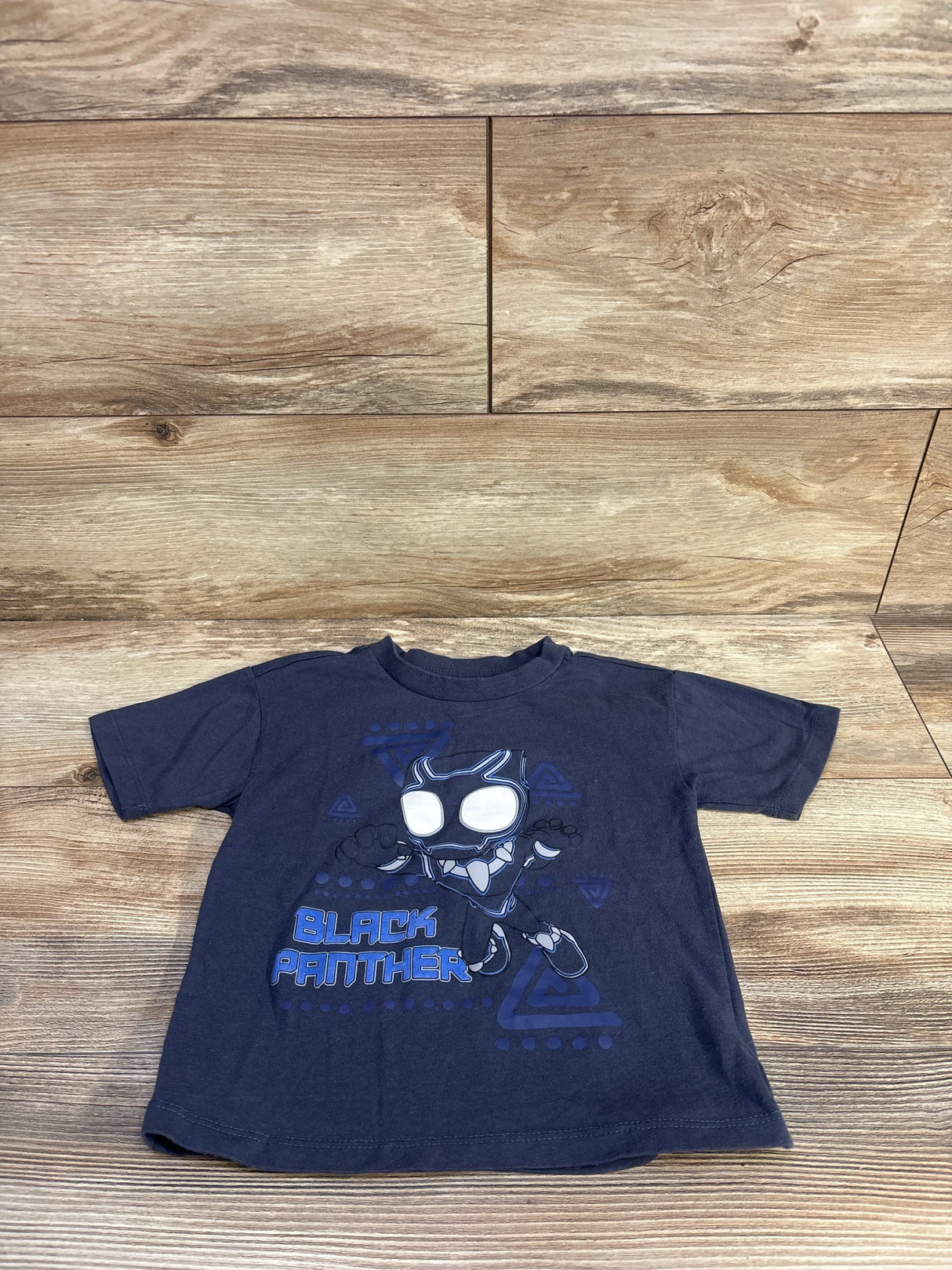 Front view of navy toddler T-shirt showcasing stylized Black Panther graphic and BLACK PANTHER text on wooden floor background
