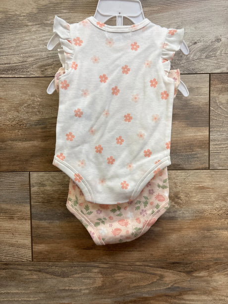 Front view of two Wonderluxe newborn flutter-sleeve bodysuits showcasing pink floral and strawberry prints on wood floor