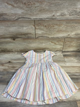 Flat lay of OshKosh girls' pastel striped button-front dress, short tied sleeves and gathered skirt on wood background