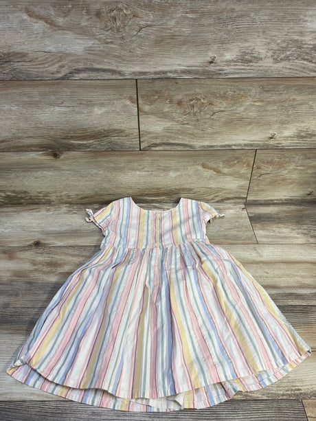 Flat lay of OshKosh girls' pastel striped button-front dress, short tied sleeves and gathered skirt on wood background