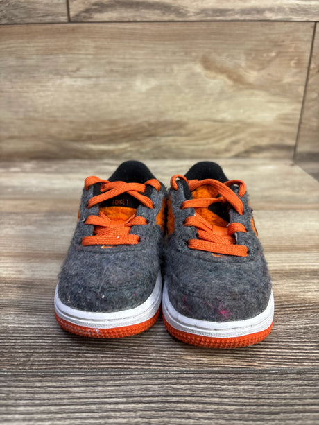 Front view of Nike Force 1 LV8 TD toddler sneakers with gray felt upper, orange laces and lining, white midsole on wood floor