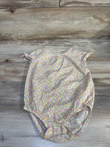 Flat lay of OshKosh yellow floral bubble romper showing tie cap sleeves and elasticized leg openings on light wood background