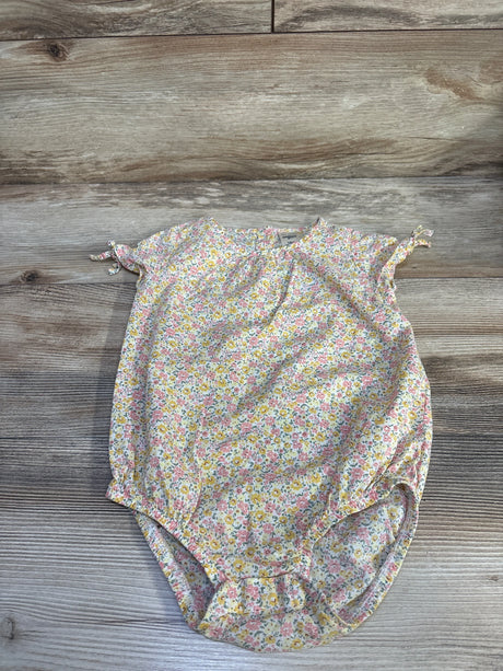 Flat lay of OshKosh yellow floral bubble romper showing tie cap sleeves and elasticized leg openings on light wood background