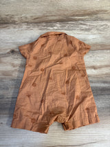 Brown baby romper with short sleeves and sun pattern on wood background