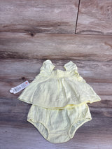 Flat lay of yellow sleeveless baby top and bloomers showing flutter sleeves and smocked bodice on wood background