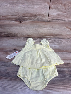 Flat lay of yellow sleeveless baby top and bloomers showing flutter sleeves and smocked bodice on wood background