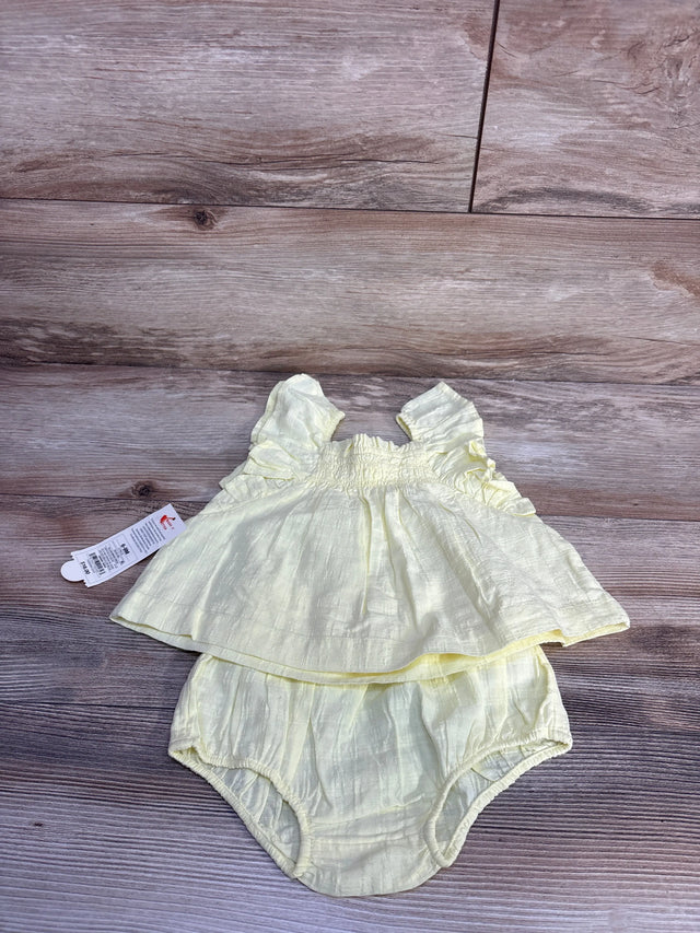 Flat lay of yellow sleeveless baby top and bloomers showing flutter sleeves and smocked bodice on wood background
