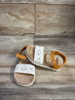Front and side view of Cat and Jack sandal showing white crochet front strap, tan ankle strap, and cushioned footbed on wood floor