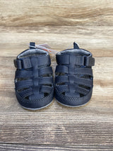 Front view of Just One You Harrison fisherman baby sandals in navy with closed toe, Velcro straps, and padded lining on wood