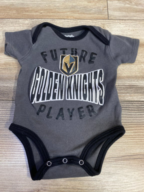 Gray Vegas Golden Knights baby onesie with 'Future Golden Knights Player' text on wood floor