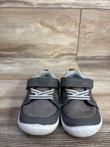 Front view of toddler grey Munchkin by Stride Rite Miller casual sneakers showing Velcro strap and white rubber soles on wood floor