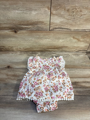 Floral baby dress romper with pink and brown flowers on wood background