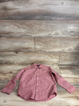 Front view of red linen-cotton long-sleeve button-up shirt (5T) with white buttons and chest pocket on wood background
