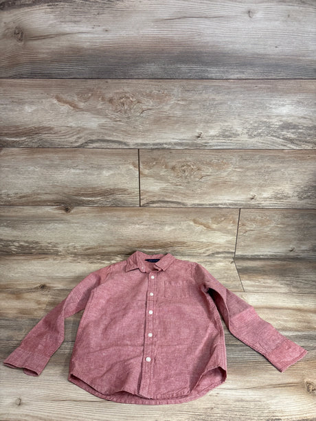 Front view of red linen-cotton long-sleeve button-up shirt (5T) with white buttons and chest pocket on wood background