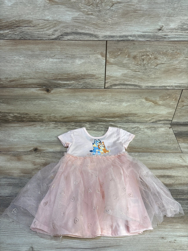 Flat-lay of pink 18m Bluey tulle dress with layered heart-print skirt and short-sleeve Bluey bodice on wood floor