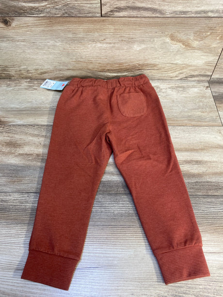 Rust orange toddler pants with elastic waist and back pocket on wood background