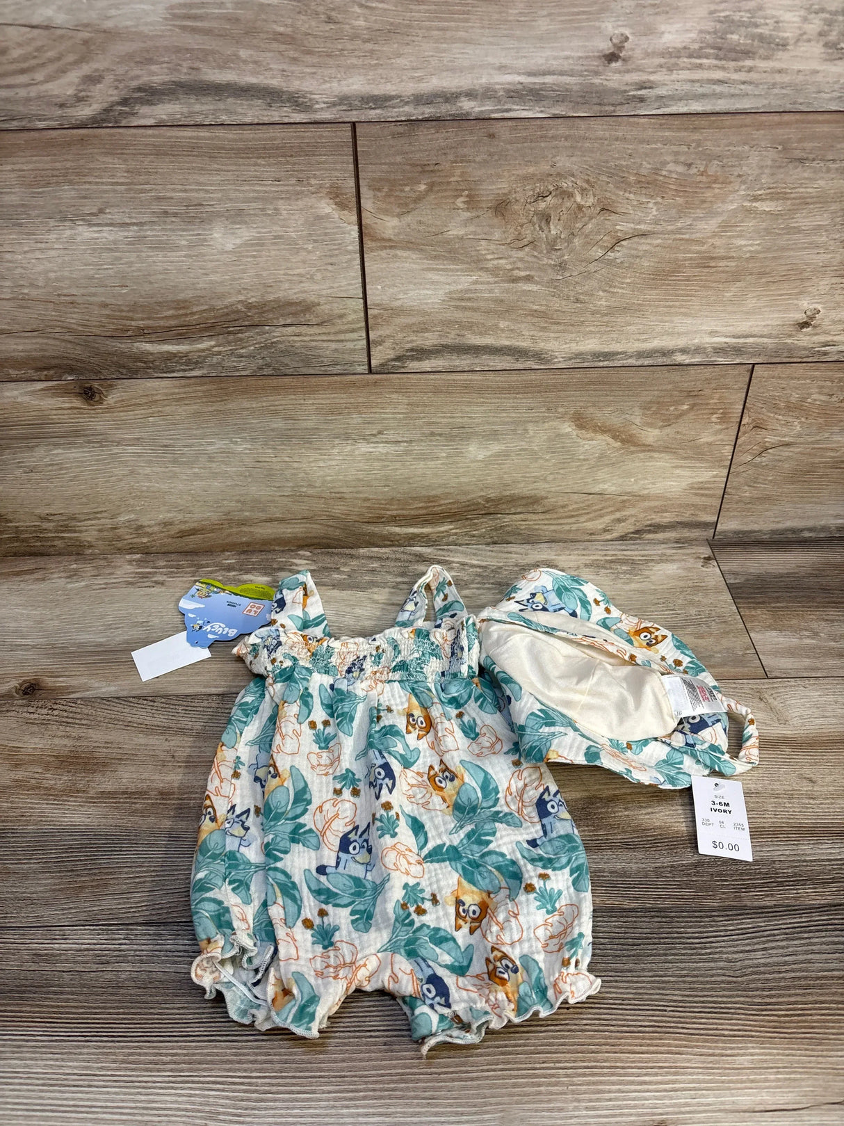Infant romper and matching hat with playful cartoon animal print, size 3-6M, on wood floor