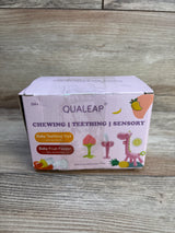 Box of Qualeap baby teething toys and fruit feeder, pink packaging on wood background