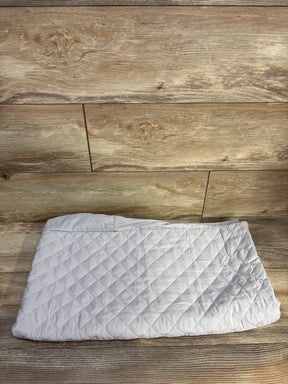 Top-down view of Pack n' Play mattress protector showcasing quilted padded grey fabric and elastic edge on wood background