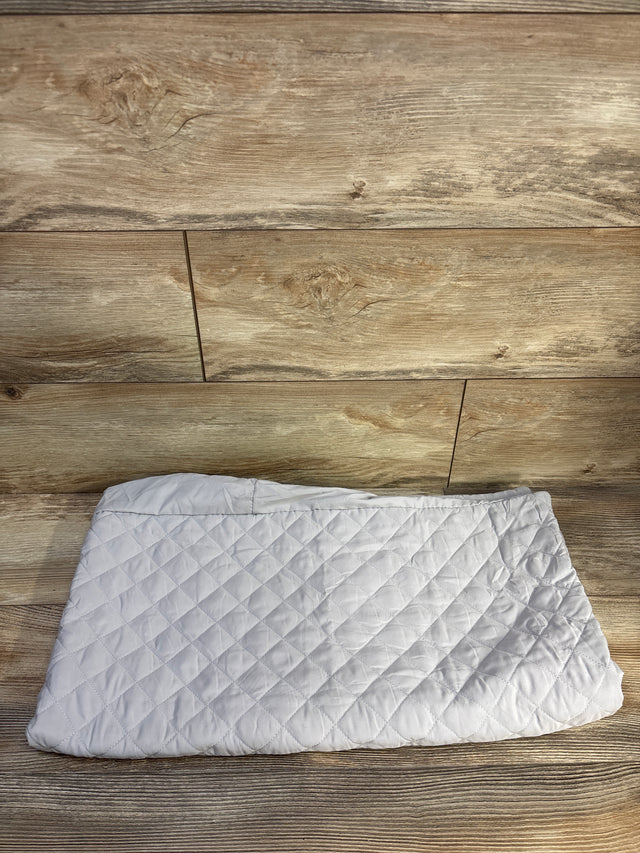 Top-down view of Pack n' Play mattress protector showcasing quilted padded grey fabric and elastic edge on wood background