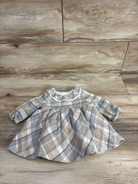 Plaid long-sleeve baby dress with ruffled collar in beige and gray tones on wooden background