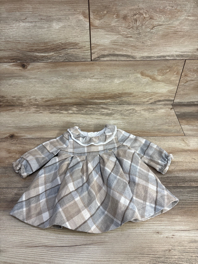 Plaid long-sleeve baby dress with ruffled collar in beige and gray tones on wooden background