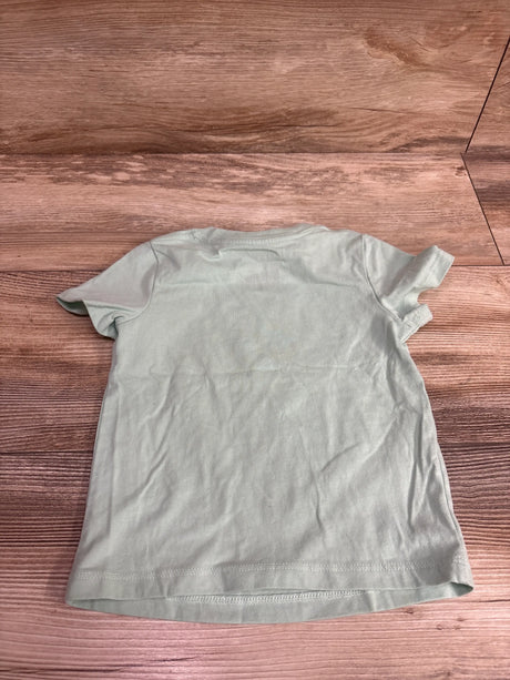 Back view of a light green Cat & Jack baby shirt size 18m on a wooden surface