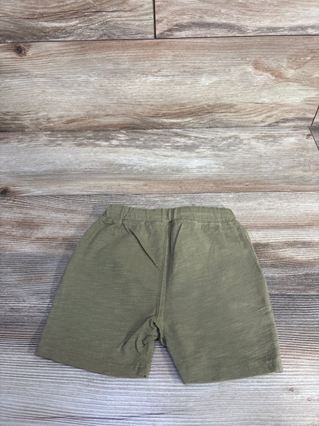 Flat lay of olive Rylee + Cru Sam toddler shorts showing elastic waistband and straight leg on wood background