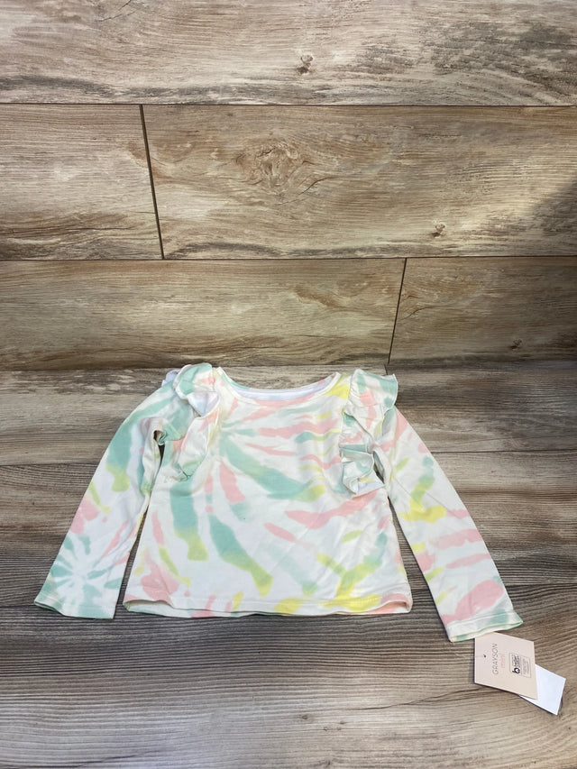 Pastel tie-dye long sleeve toddler shirt with ruffle shoulders on wood background