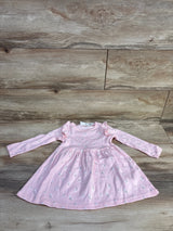 Flat lay of pink long-sleeve floral toddler dress with ruffle shoulders and gathered skirt on wood background