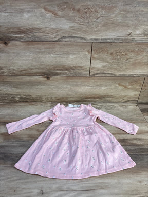 Flat lay of pink long-sleeve floral toddler dress with ruffle shoulders and gathered skirt on wood background