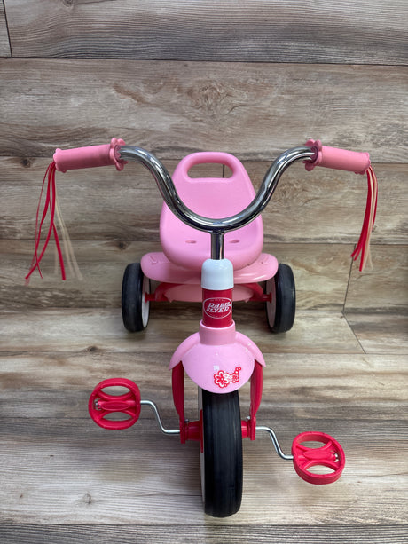 Front view of pink Radio Flyer Ready to Ride Folding Trike with chrome handlebars, red pedals, and tassels