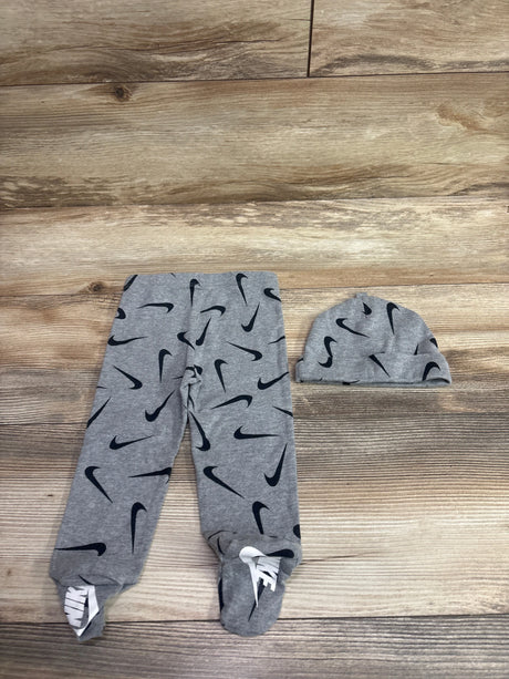 Top view of Nike two piece footed leggings and hat set in grey, size 6 months, with black Swoosh pattern on wood background