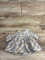 Neutral plaid long-sleeve baby dress with gathered skirt on wood floor background