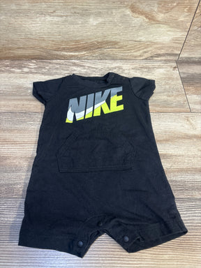 Black short sleeve baby romper with NIKE logo, front pocket, snap bottom, on wood floor