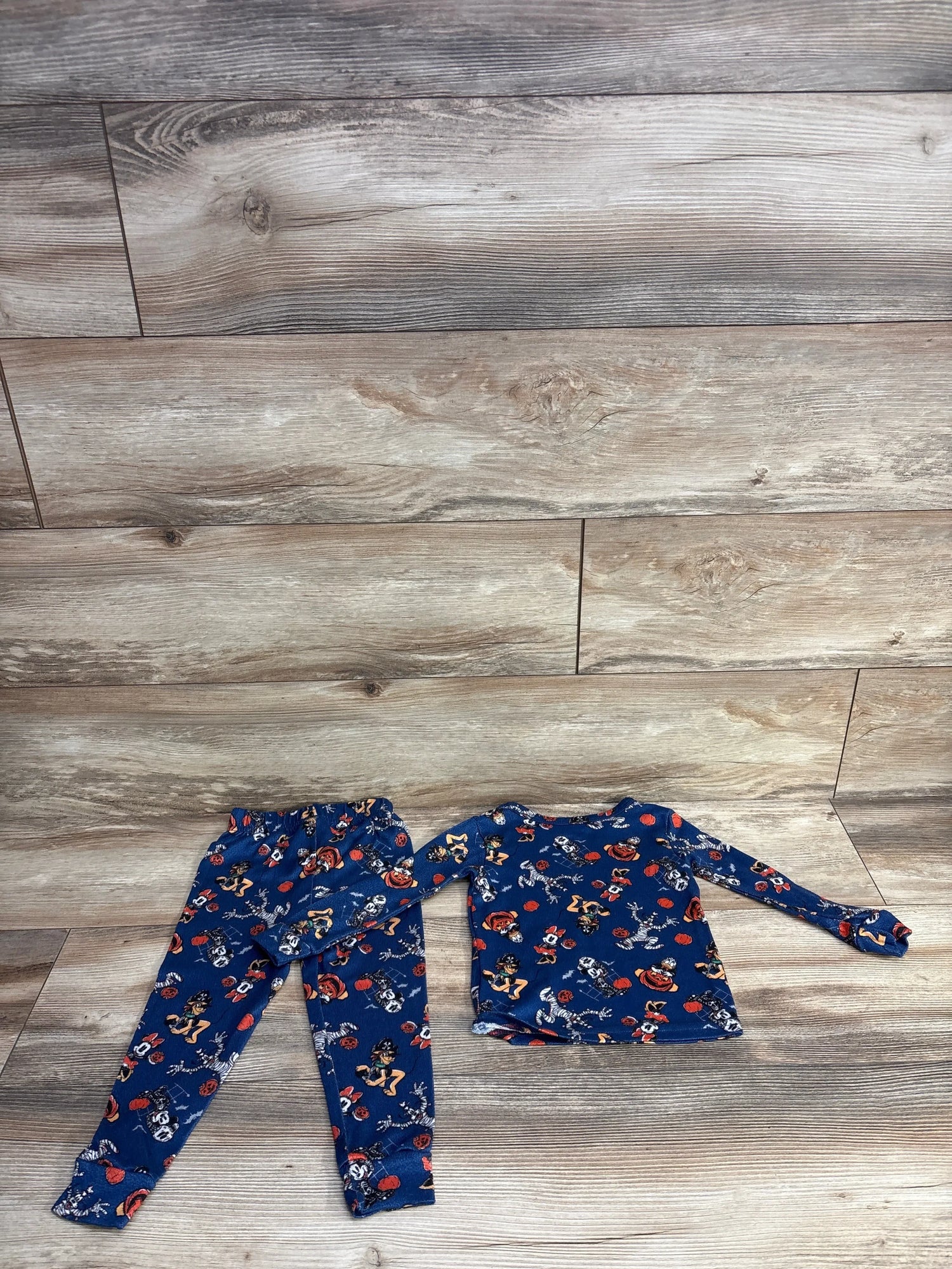 Blue Halloween-themed kids pajama set with pirate and pumpkin print, laid on wood floor