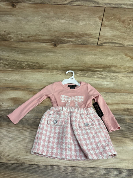 Front view of pink Girls First long sleeve dress with ribbed sleeves, glittery bow, and patterned skirt on a hanger