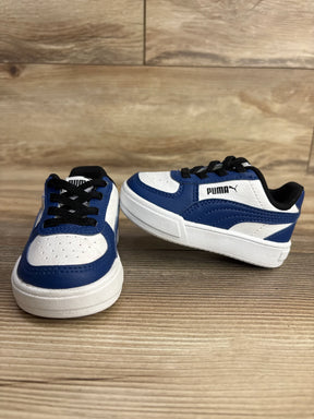 Blue and white kids sneakers with black laces on wooden floor