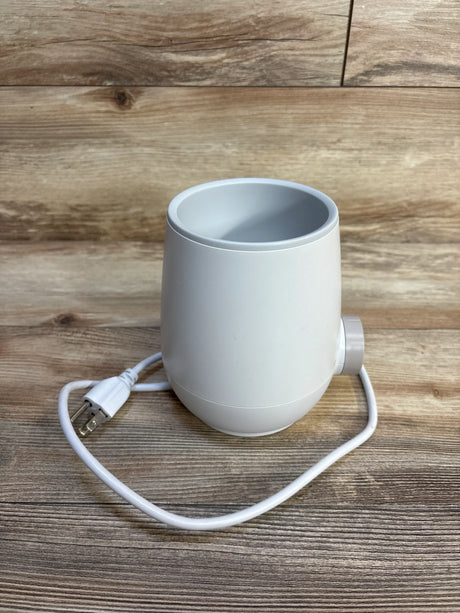 White electric baby bottle warmer on wooden surface with power cord