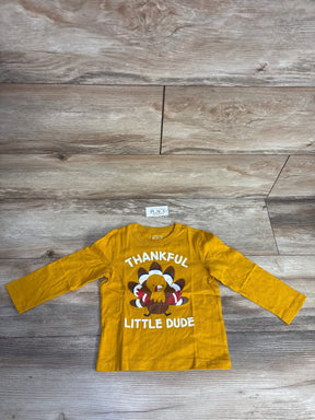 Mustard yellow toddler long sleeve shirt with turkey and 'Thankful Little Dude' text on wood floor