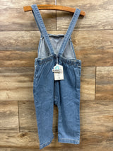 Kids blue denim overalls with adjustable straps hanging on wooden hanger