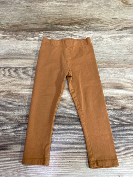Front view of C&C California Kids leggings in caramel showcasing elastic waistband and straight legs on a wood-grain background